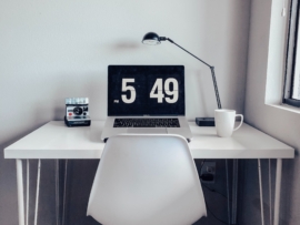 image shows a working from home setup with a mac computer sitting on top of a white desk